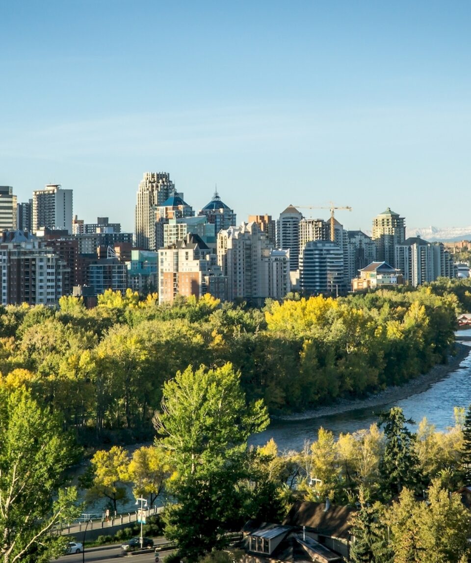 Calgary downtown at morning spring with river in foreground and mountains in background