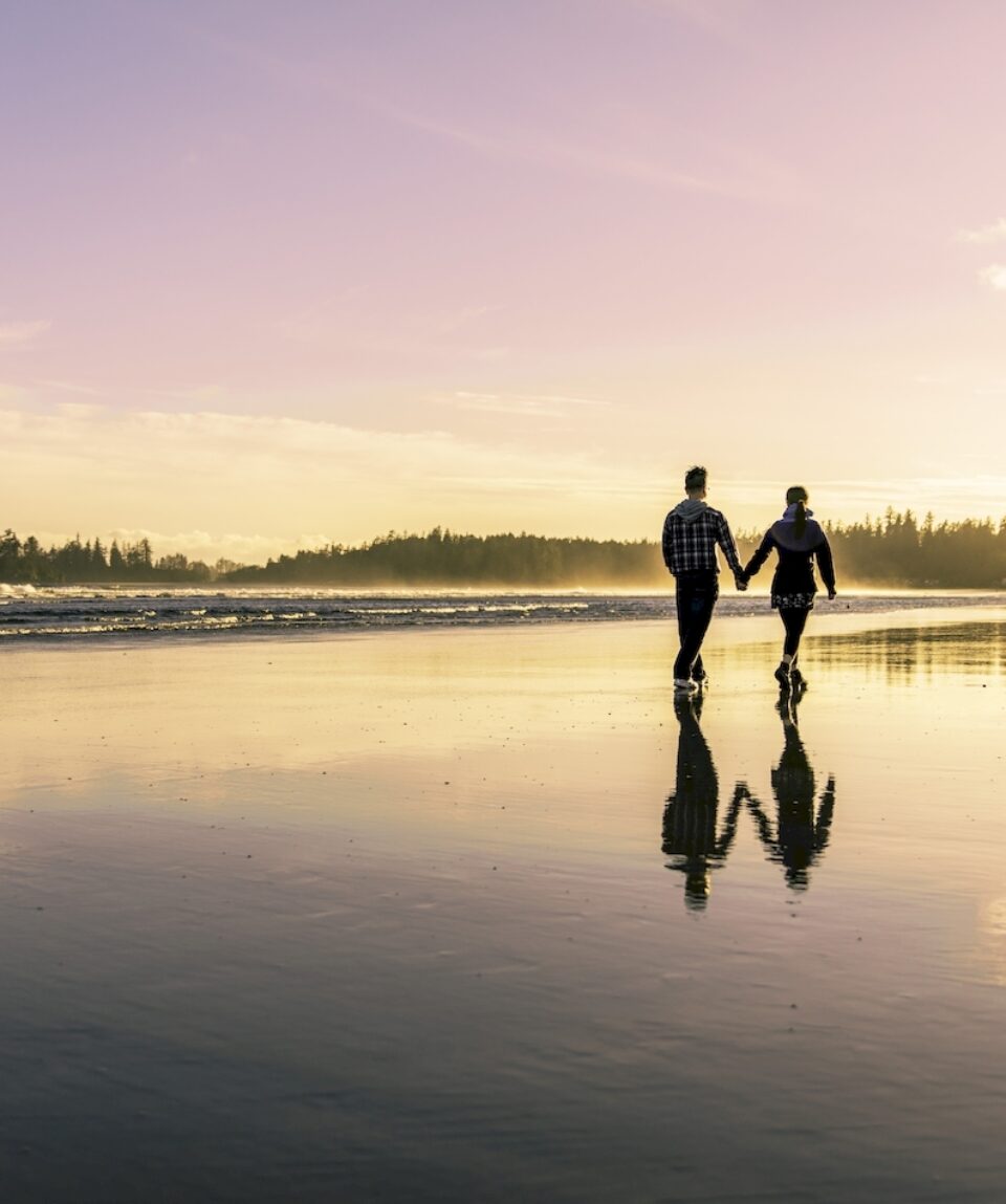 Couple going for a walk as the sun sets at Long Beach in Tofino during the summer