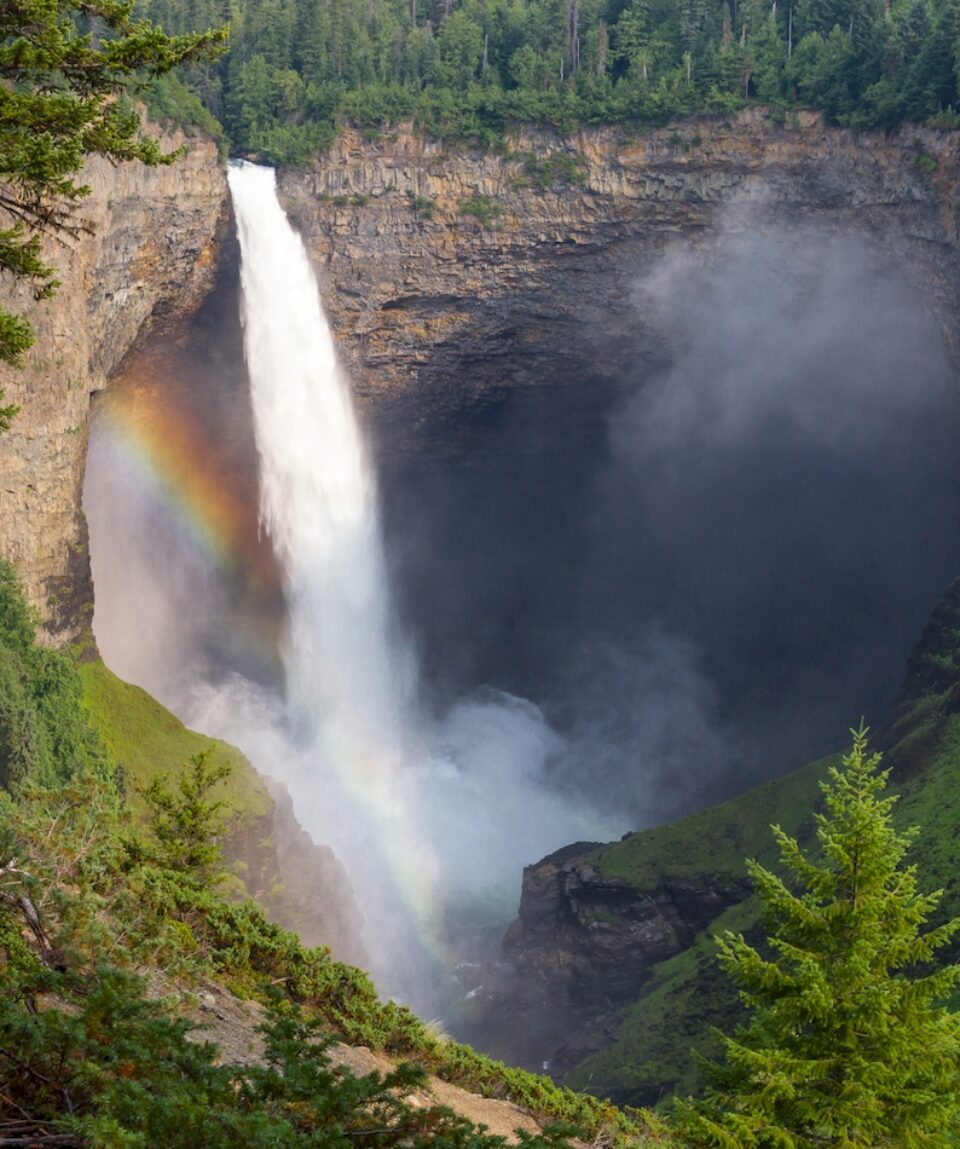 Rainbow appears in mist at sunlit Helmcken Falls in Wells Gray Provincial Park