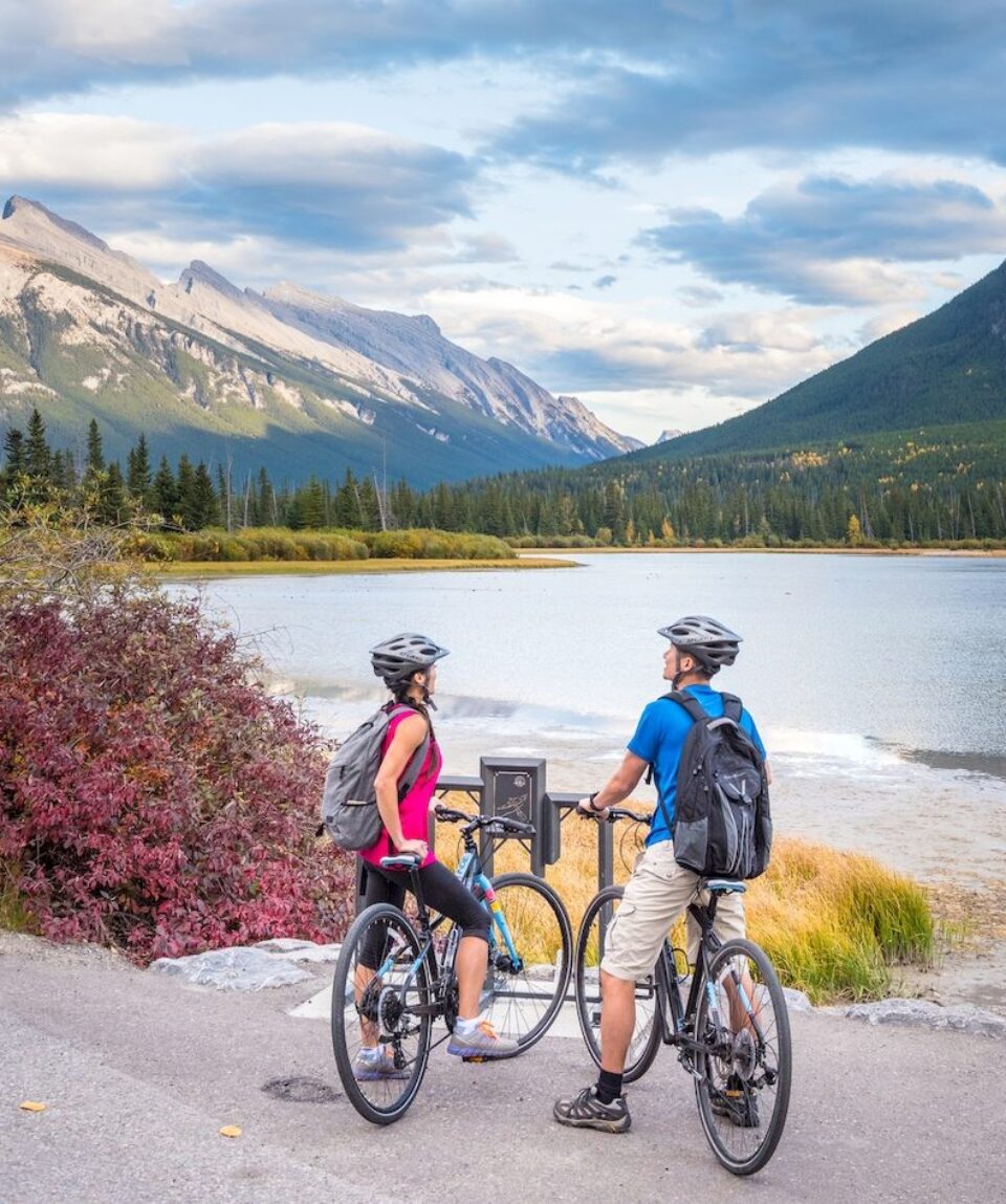 A couple of bikers take in the view from Vermillion Lakes Road with Mount Rundle in the background. Banff National Park